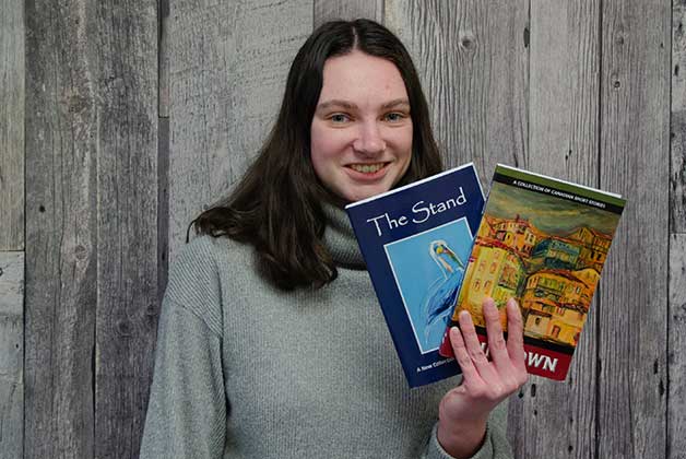 Headshot of Brianna North holding books with her signature